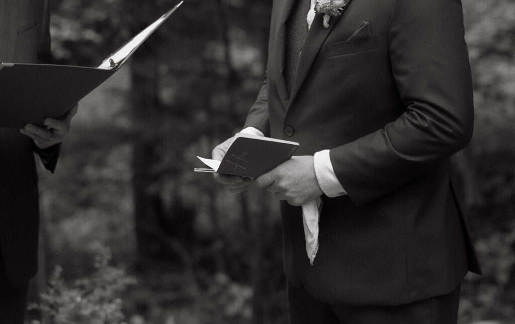 groom holding his vow book during the ceremony of his wedding in Vermont