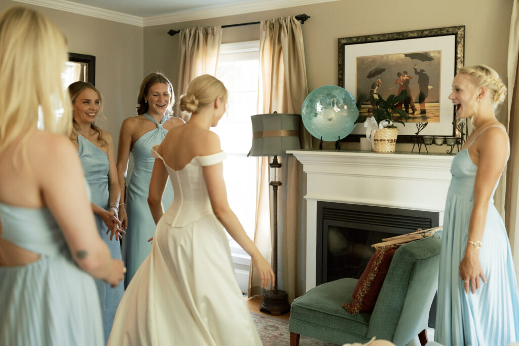 bridesmaids gawking over bride as she spins in her wedding dress after she is ready 