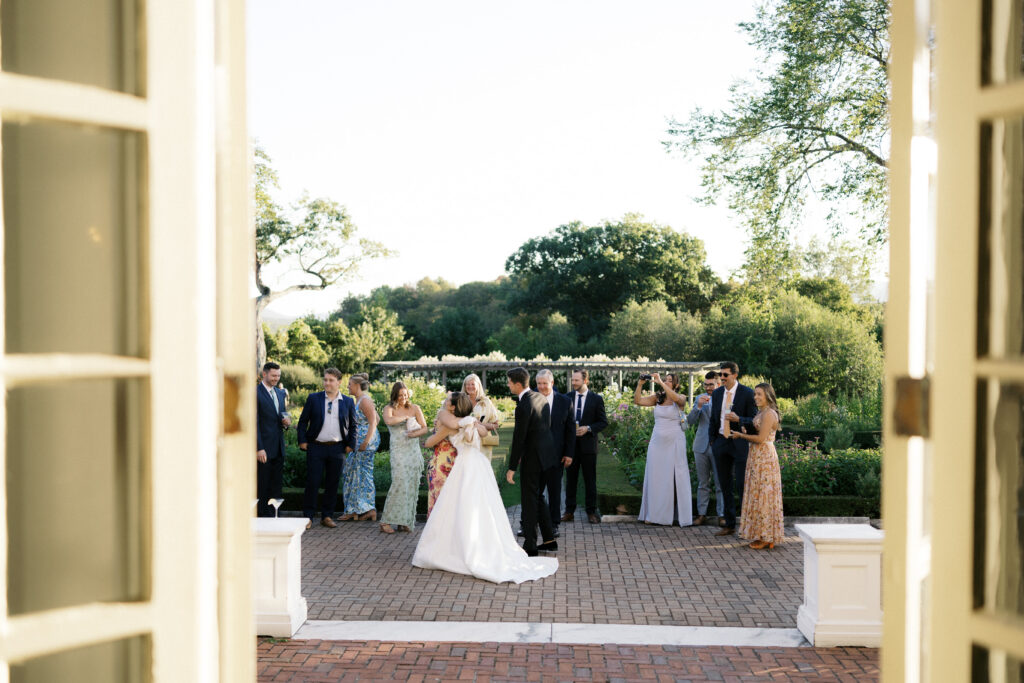 bride hugging guest during cocktail hour at hildene lincoln family home in manchester, vermont at their summer wedding