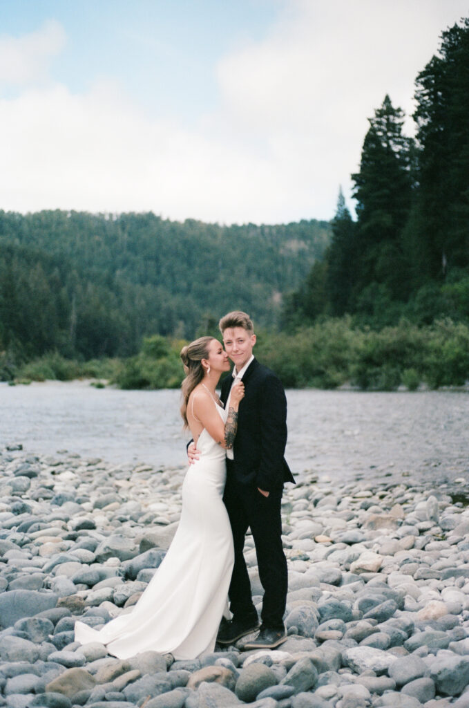 Newlyweds walking beside a river in the California redwoods, captured on 35mm film