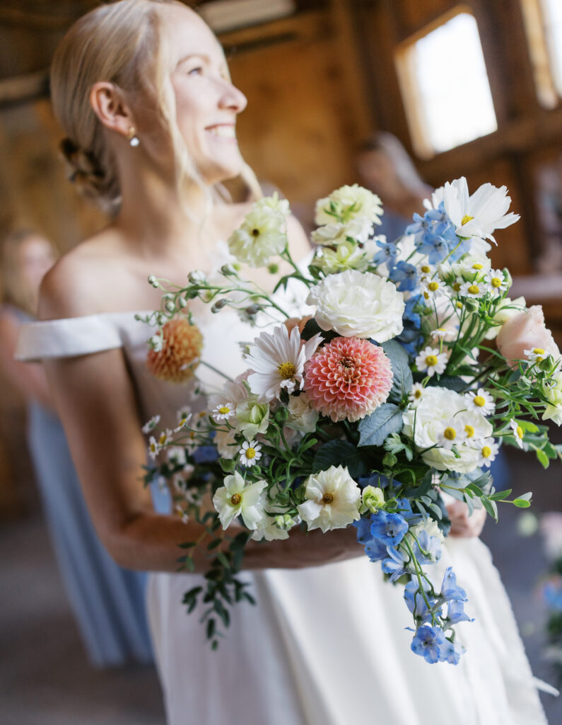 gorgeous summer florals being held by bride at her augst wedding in Williston Vermont