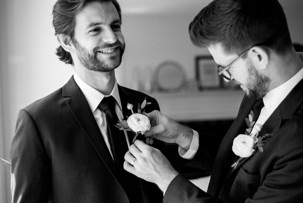 Best man pinning the groom’s boutonniere, photographed on 35mm film