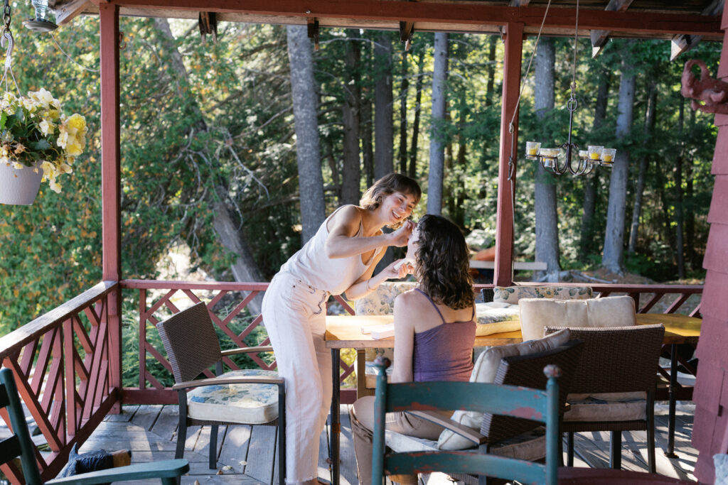 Bride helping her sister with makeup while getting ready at a New Hampshire wedding venue